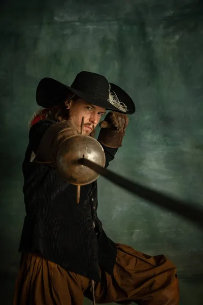 Retrato de brutal hombre horrendo, pirata medeival en traje vintage sosteniendo espada aislada sobre fondo oscuro. Juego de espadas — Foto de Stock