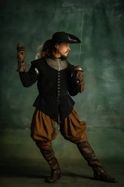 Портрет жорстокого чоловіка, пірата медейвалів у вінтажному костюмі, що тримає меч ізольованим на темному тлі. Меч. — стокове фото