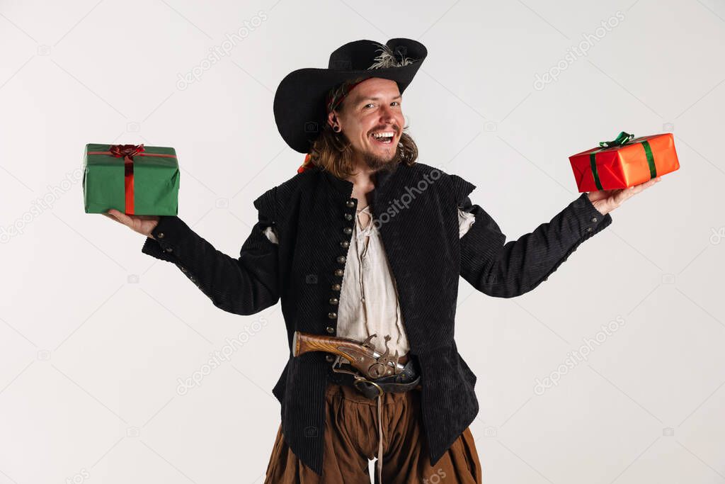 Cropped portrait of man, pirate in vintage costume holding two gift boxes isolated over white background