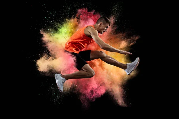 Genç adamın yaratıcı kolajı, profesyonel atlet, koşucu eğitimi siyah arka plandaki renkli barut patlaması üzerine izole edilmiş. El ilanı — Stok fotoğraf