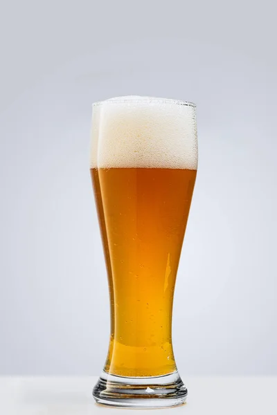 Verre de bière mousseuse lager isolé sur fond gris. Notion de boissons alcoolisées — Photo
