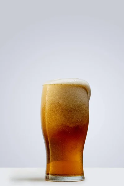 Egy pohár világos habos sör szürke háttérrel. Az alkoholtartalmú italok fogalma — Stock Fotó