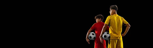 Collage di ragazzo e adolescente, calciatori in uniforme gialla e rossa in posa isolata su sfondo nero. Vista posteriore — Foto Stock