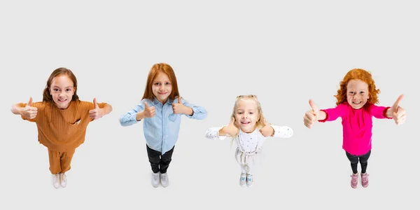 Collage van vier vrolijke kinderen, kinderen, meisjes tonen duimen omhoog, als gebaar geïsoleerd over witte achtergrond — Stockfoto