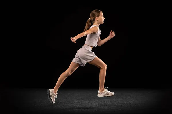 Retrato de cuerpo entero de adolescente, atleta corriendo, entrenamiento aislado sobre fondo negro. Ganar — Foto de Stock