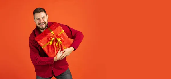 Portrait recadré d'homme joyeux avec boîte cadeau tourbière posant isolé sur fond rouge — Photo