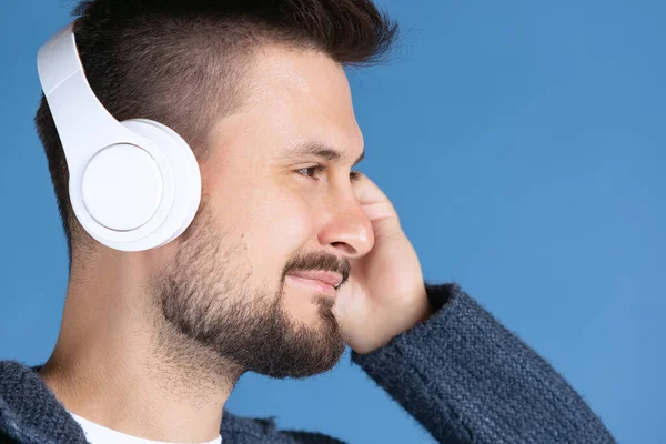 Közelkép portré az ember hallgat zenét fehér fejhallgató elszigetelt kék háttér — Stock Fotó