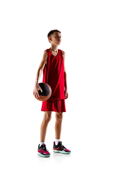 Beyaz arka planda izole edilmiş kırmızı üniformalı profesyonel basketbolcu, genç bir çocuğun tam boy portresi. — Stok fotoğraf