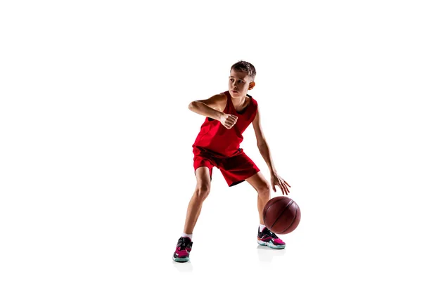 Ganzkörperporträt eines Jungen, Basketballspielers in roter Uniform, der isoliert vor weißem Hintergrund trainiert. Bounce pass — Stockfoto