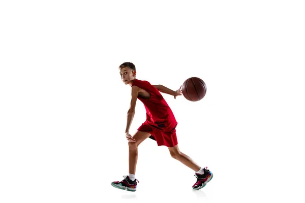 Full längd porträtt av tonåring, pojke i röd uniform spelning, träning basket isolerad över vit bakgrund — Stockfoto