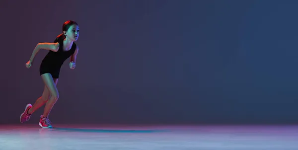 Teljes hosszúságú portré tinilányról, atléta futásról, edzés elszigetelve a lejtős kék lila háttér felett neon fényekben. Szórólap — Stock Fotó