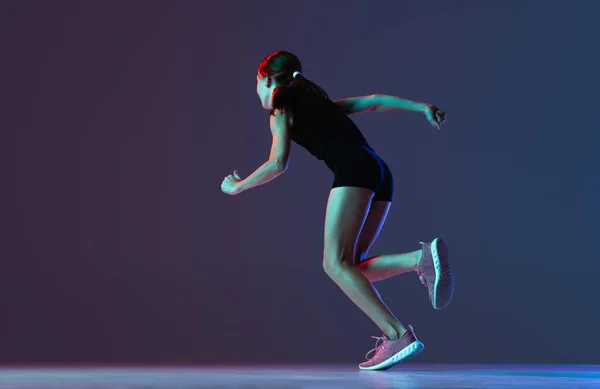 霓虹灯下女孩、职业运动员、赛跑选手在深蓝色紫色背景上被隔离的画像 — 图库照片
