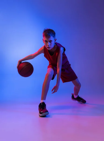 Ganztägiges Porträt des Basketballtrainings, Dribbeln isoliert über gradienten blauen Hintergrund in Neonlicht — Stockfoto