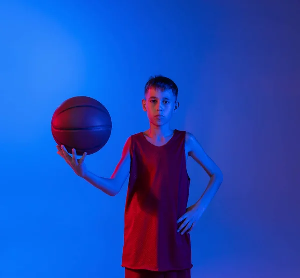Porträt eines Jungen, Basketballspieler posiert isoliert über Gradienten blau lila Hintergrund in Neonlichtern — Stockfoto