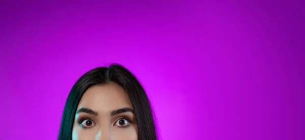 Ausgeschnittenes Bild schöner weiblicher Augen weit geöffnet, die Kamera isoliert über violettem Hintergrund betrachtend — Stockfoto