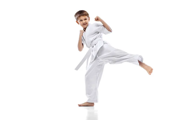 Полноразмерный портрет маленького мальчика, каратиста в белом кимоно тренировки изолированы на белом фоне — стоковое фото