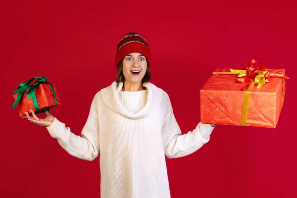 Vágott portré gyönyörű izgatott nő kezében két nagy ajándék dobozok elszigetelt vörös háttérrel. Ünneplés — Stock Fotó