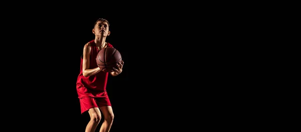 年轻男孩的肖像，篮球运动员在运动，训练孤立的黑色背景 — 图库照片