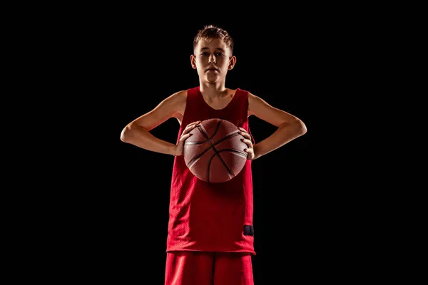 Retrato de cuerpo entero de adolescente, jugador de baloncesto en uniforme rojo con pelota posando aislado sobre fondo negro —  Fotos de Stock