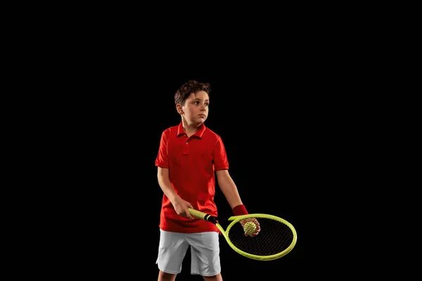 Cropped portrait of boy, tennis player in motion, training isolated over black backgound — Stock Photo, Image