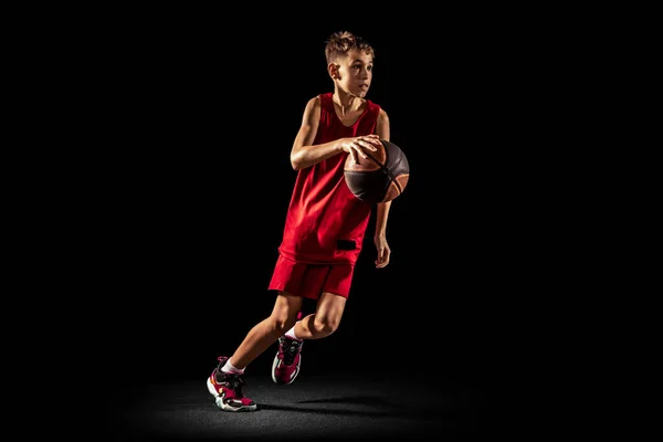 Full-length portrait of teen boy, professional backetball player in motion, training isolated over black background. Ντρίμπλα — Φωτογραφία Αρχείου