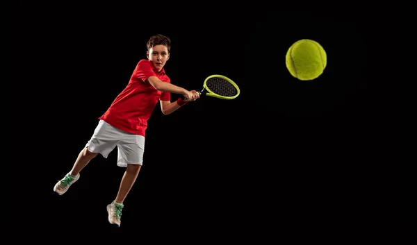 Полнометражный портрет мальчика, теннисист в движении, мячик с ракеткой на черном фоне — стоковое фото