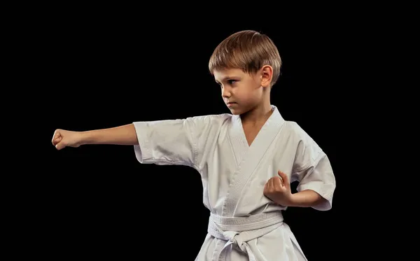 Портрет маленького мальчика, спортсмен тренирует боевое искусство, карате изолирован на черном фоне — стоковое фото