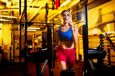 Sportif, fit, kaslı genç kız eğitiminin kesilmiş portresi koşu bandında kardiyo yapıyor.