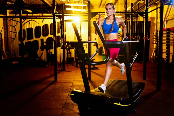 Spor salonundaki renkli spor giyim treninde kardiyo egzersizleri yapan, koşu bandında koşan genç bir kadının kesilmiş portresi.. — Stok fotoğraf
