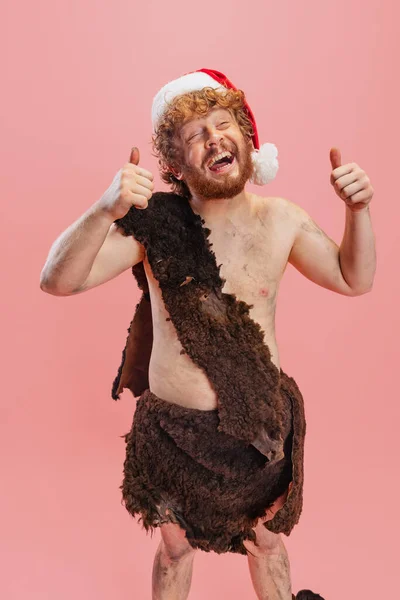 Retrato de homem alegre em caráter de neandertal vestindo pano de pele animal alegremente posando isolado sobre fundo rosa — Fotografia de Stock