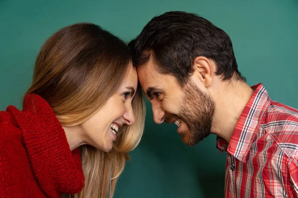 Retrato de vista lateral cortada de casal em pé, batendo cabeças juntos e olhando uns para os outros isolado sobre fundo verde — Fotografia de Stock