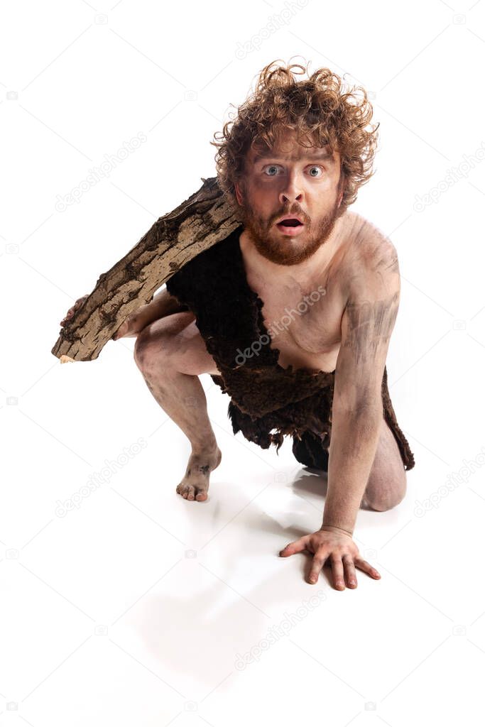 Full-length portrait of dirty man in character of neanderthal climbing with log isolated over white background