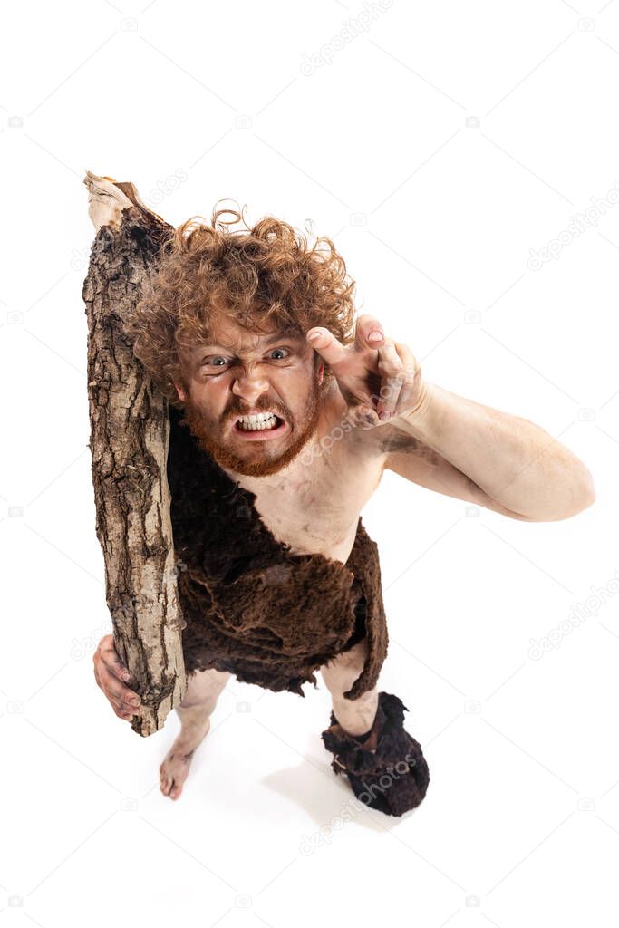Full-length portrait of angry man in character of neanderthal holding log isolated over white background