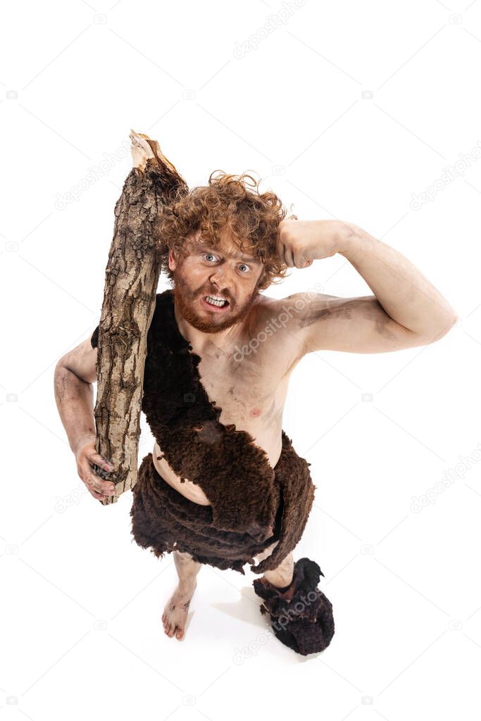 Full-length portrait of dirty man in character of neanderthal showing muscles isolated over white background