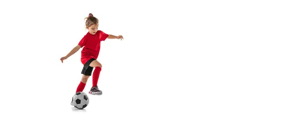 Full längd porträtt av liten flicka, barn spelar fotboll, utbildning, dribbling boll isolerad över röd bakgrund. Flygblad — Stockfoto