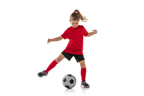 Kırmızı üniformalı, beyaz arka planda izole bir şekilde futbol oynayan küçük bir kızın tam boy portresi. — Stok fotoğraf