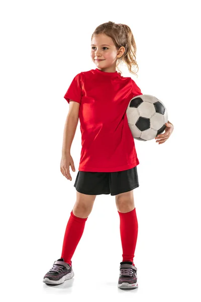 Retrato de niña, niña, futbolista en uniforme rojo de pie con pelota aislada sobre fondo blanco —  Fotos de Stock