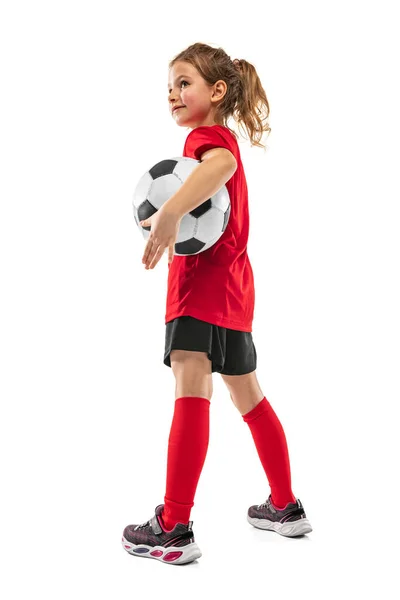 Retrato de niña, niña, en uniforme de futbolista rojo posando con pelota aislada sobre fondo blanco —  Fotos de Stock