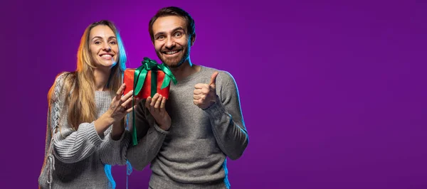 Retrato recortado de alegre casal feliz segurando férias caixa de presente isolado sobre fundo roxo. Folheto — Fotografia de Stock