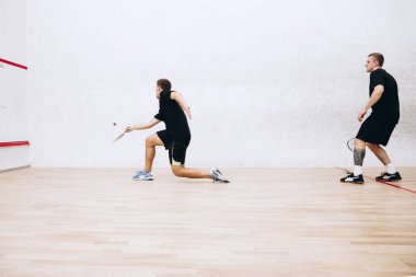 Spor stüdyosunun arka planında izole edilmiş squash oynayan hareketli iki gencin uzun kenarlı portresi.