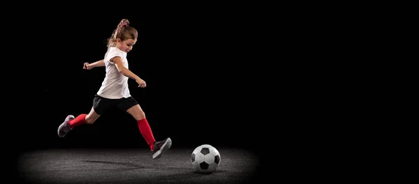 Retrato de cuerpo entero de niña en movimiento, entrenando, jugando al fútbol aislado sobre fondo negro. Volante —  Fotos de Stock
