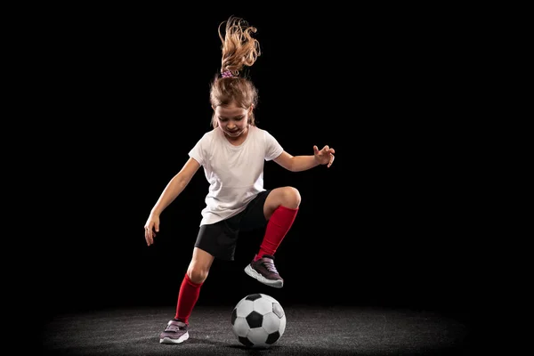 Ολόσωμο πορτραίτο παιχνιδιάρικου κοριτσιού, παιδί σε κίνηση, δράση, εκπαίδευση απομονωμένο σε μαύρο φόντο. Ντρίμπλα — Φωτογραφία Αρχείου