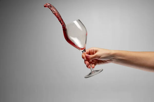 Θηλυκό χέρι Holdig γυαλί με κόκκινο κρασί απομονώνονται σε γκρι φόντο — Φωτογραφία Αρχείου