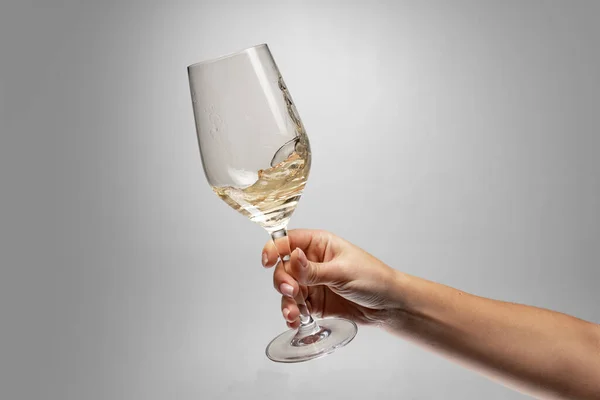 Καλλιεργημένη εικόνα του γυναικείου χεριού που κρατά το γυαλί με λευκό κρασί απομονωμένο σε γκρι φόντο — Φωτογραφία Αρχείου