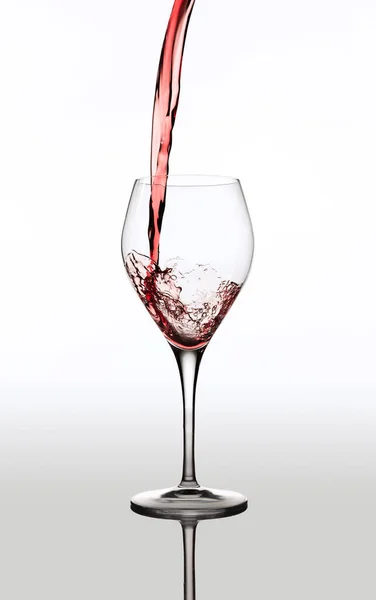 Image de délicieux vin rouge versé dans un verre isolé sur fond gris — Photo