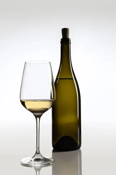 Imagem completa de garrafa de vinho e vidro preenchido com vinho branco isolado sobre fundo cinza — Fotografia de Stock