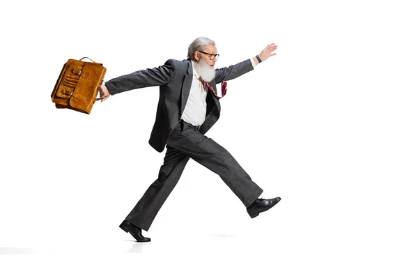 Full-length portret van senior man, werknemer in een pak met aktetas vrolijk rennend naar het werk geïsoleerd over witte achtergrond — Stockfoto