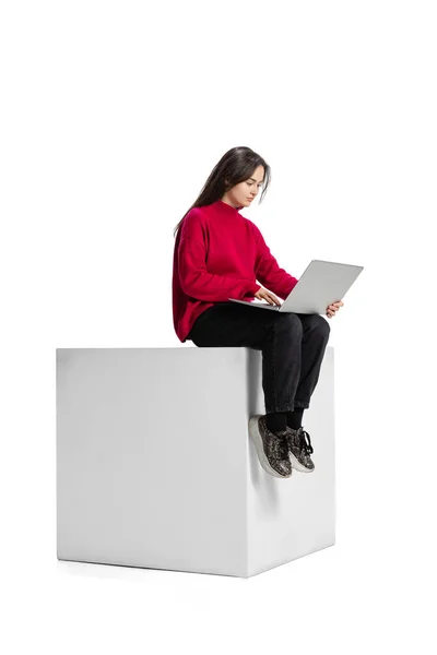 Полнометражный портрет молодой девушки, работающей над проектом, печатающей на ноутбуке на белом фоне — стоковое фото