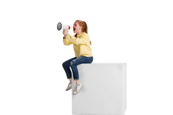 Full-length portrait of young girl shouting in megaphone with anger isolated over white background — стоковое фото