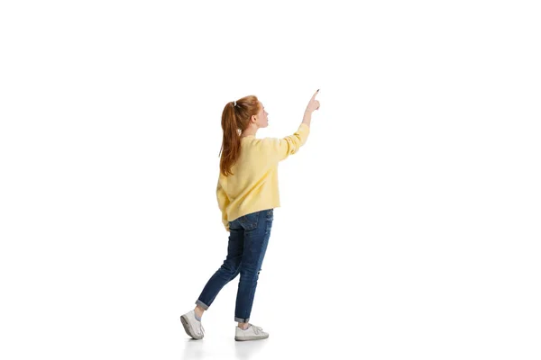 Полнометражный портрет молодой девушки, указывающей на доску, показывающей информацию, изолированную на белом фоне — стоковое фото
